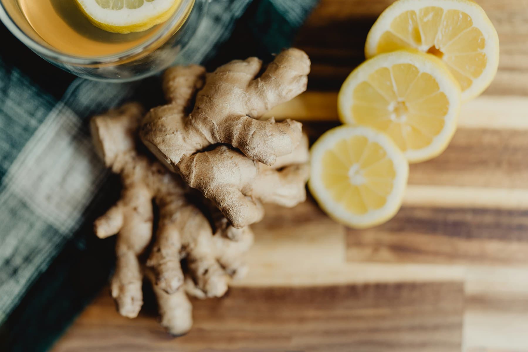 Fresh ginger root and sliced lemons on a cutting board
